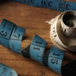 A detailed view of rolled blue and white measuring tapes on a wooden background, symbolizing measurement.