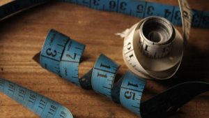 A detailed view of rolled blue and white measuring tapes on a wooden background, symbolizing measurement.